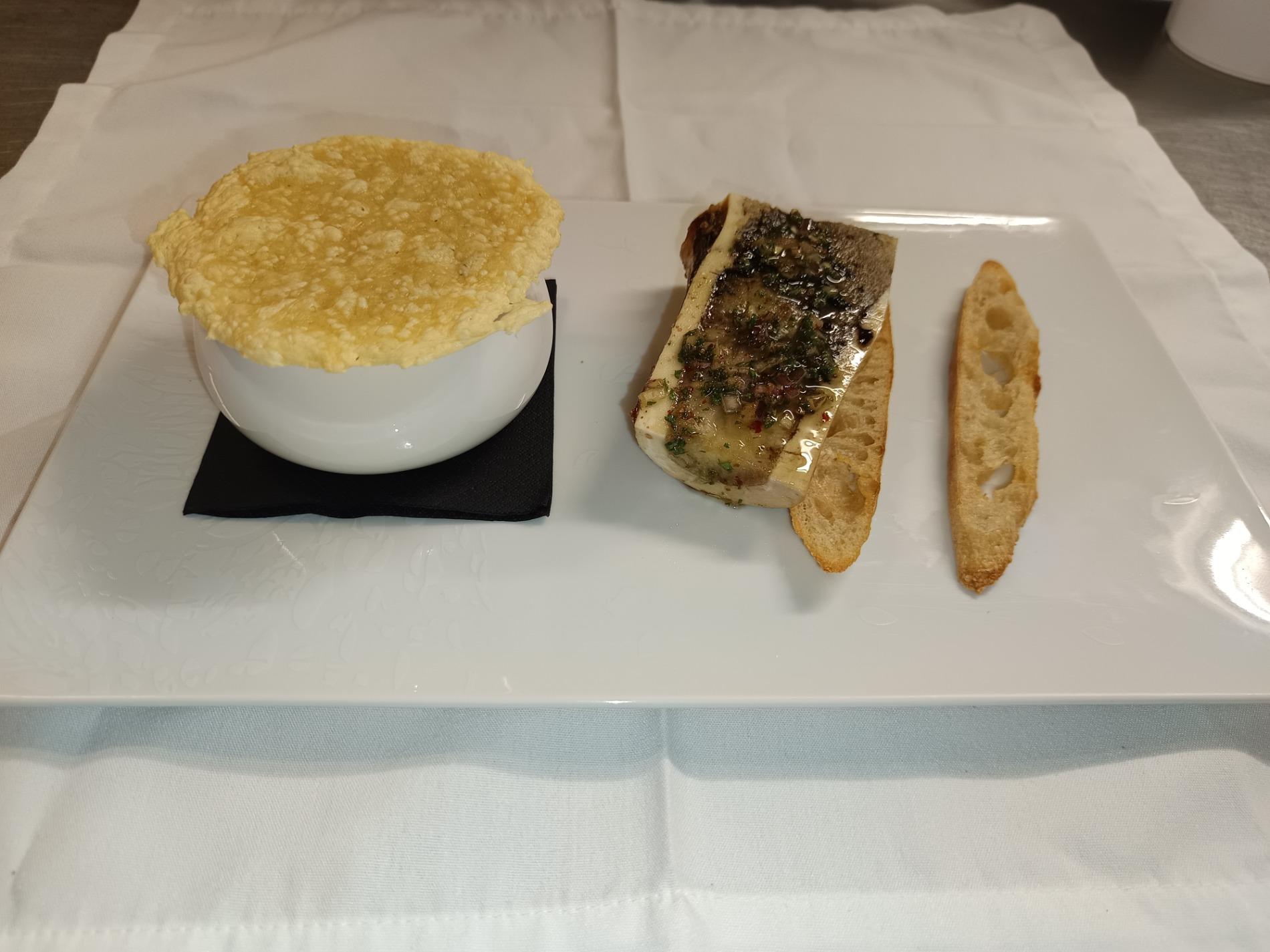 -  La soupe à l’oignon, surmontée d’une tuile d’emmental, accompagnée d’un os à moelle et de condiments.