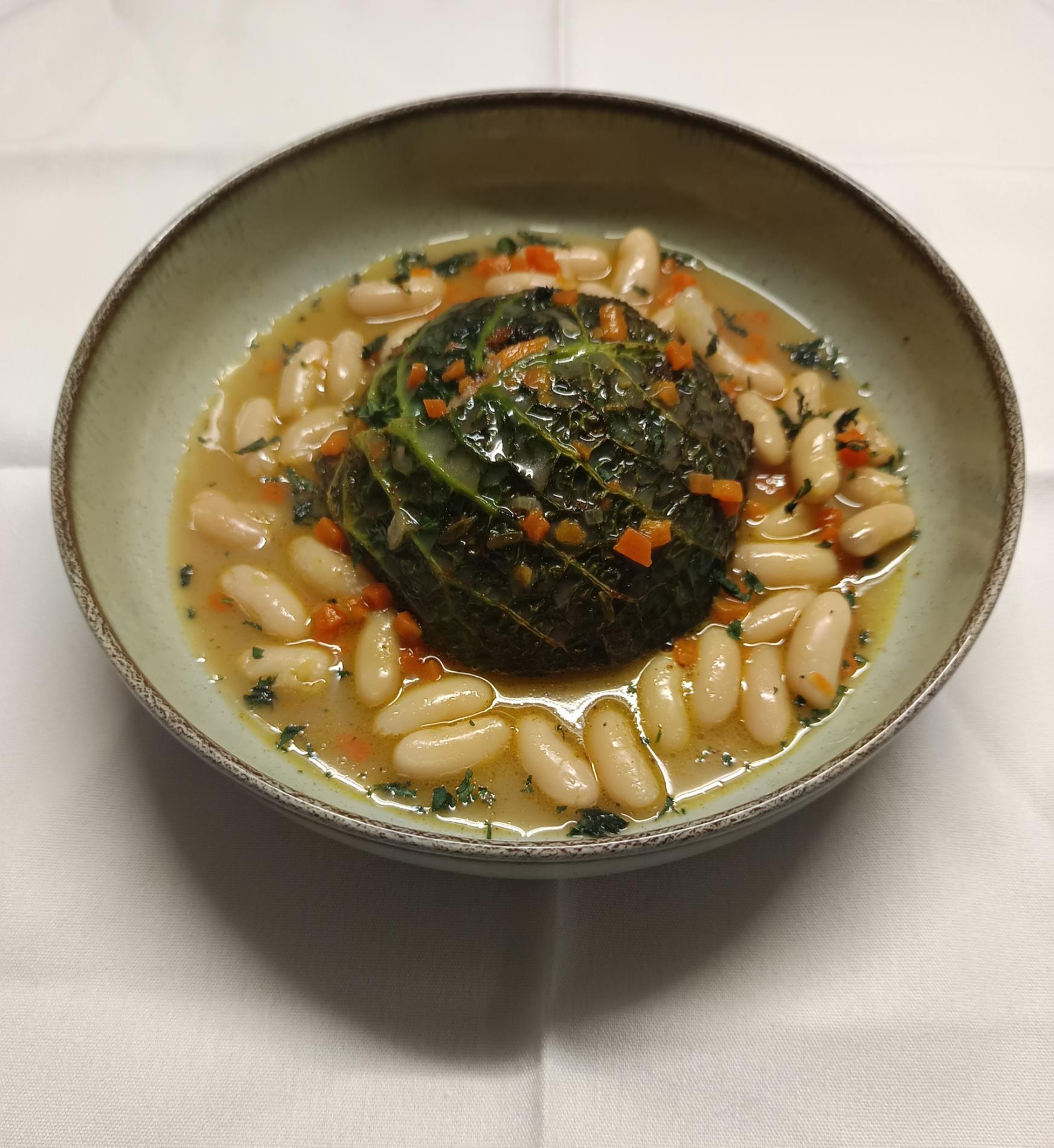 - Feuilles de chou garnies d’agneau confit servies avec des haricots cocos parfumés à la sarriette.